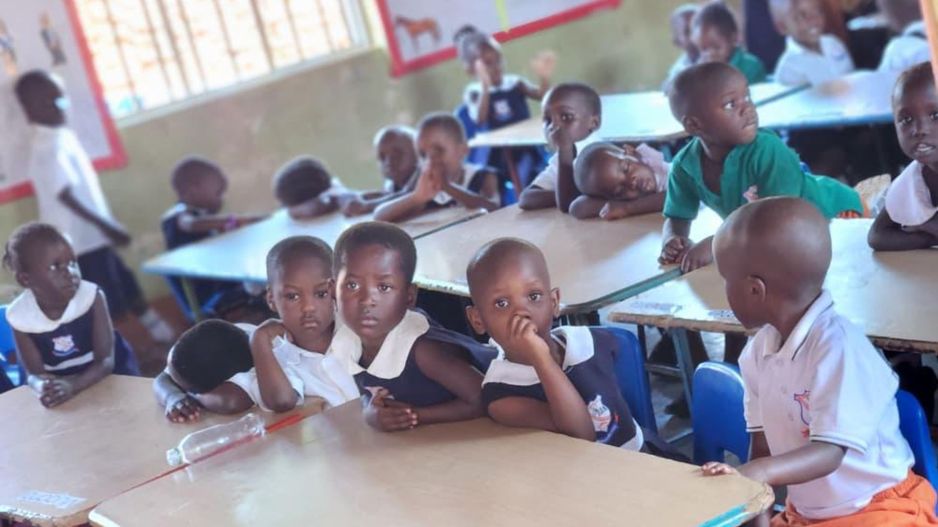 Children in uniform holding books in a classroom